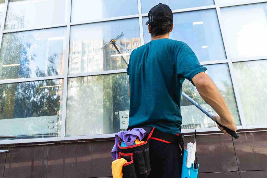 Technician using a water-fed pole to clean exterior windows